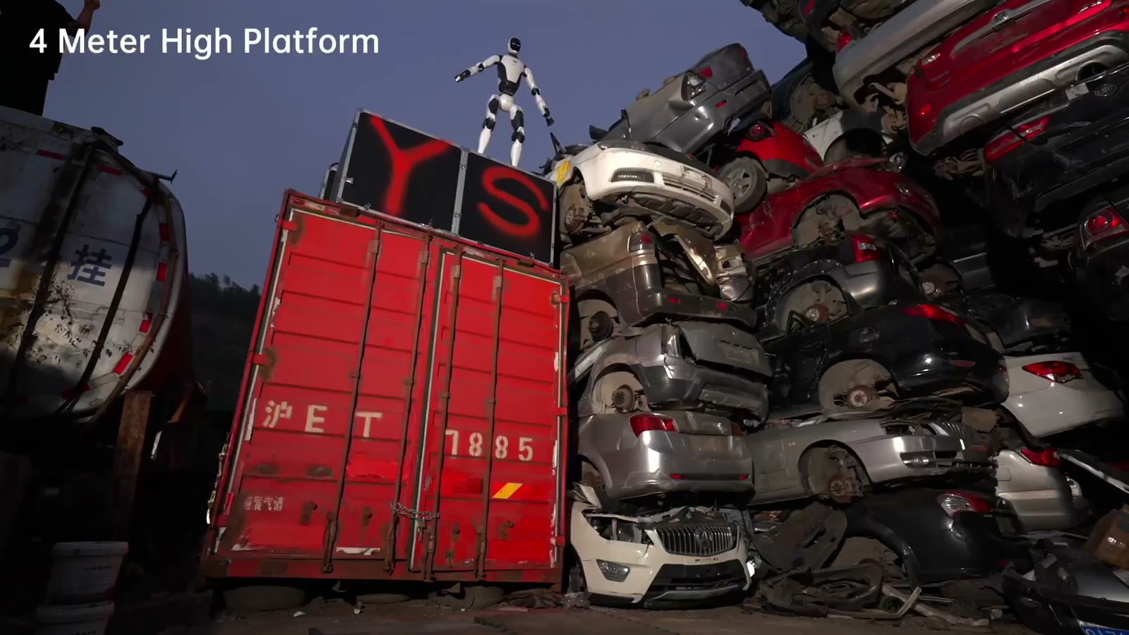 The H2‑X standing on top of a red shipping container beside a stack of wrecked cars, under an on-screen label reading 4 Meter High Platform